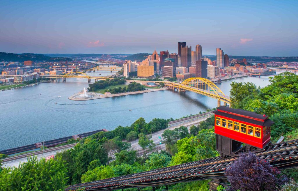 Pittsburgh skyline with yellow bridges and the Duquesne Incline overlooking the confluence of rivers.