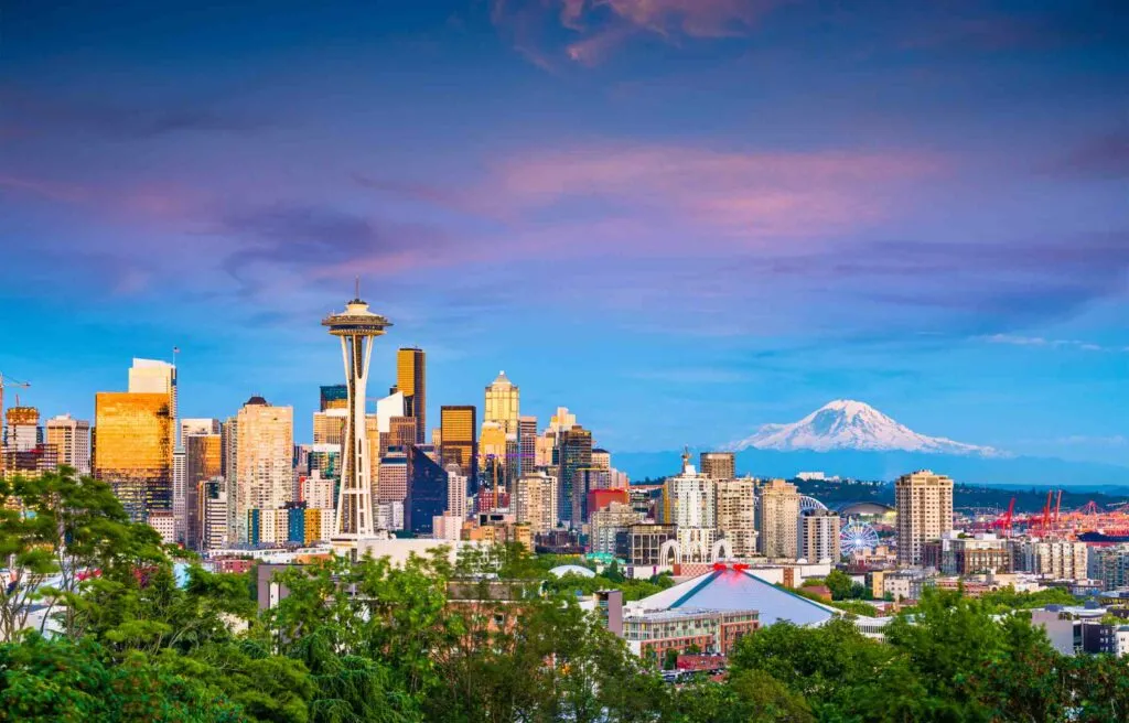 Seattle Washington skyline with the Space Needle and Mount Rainier in the background at sunset.
