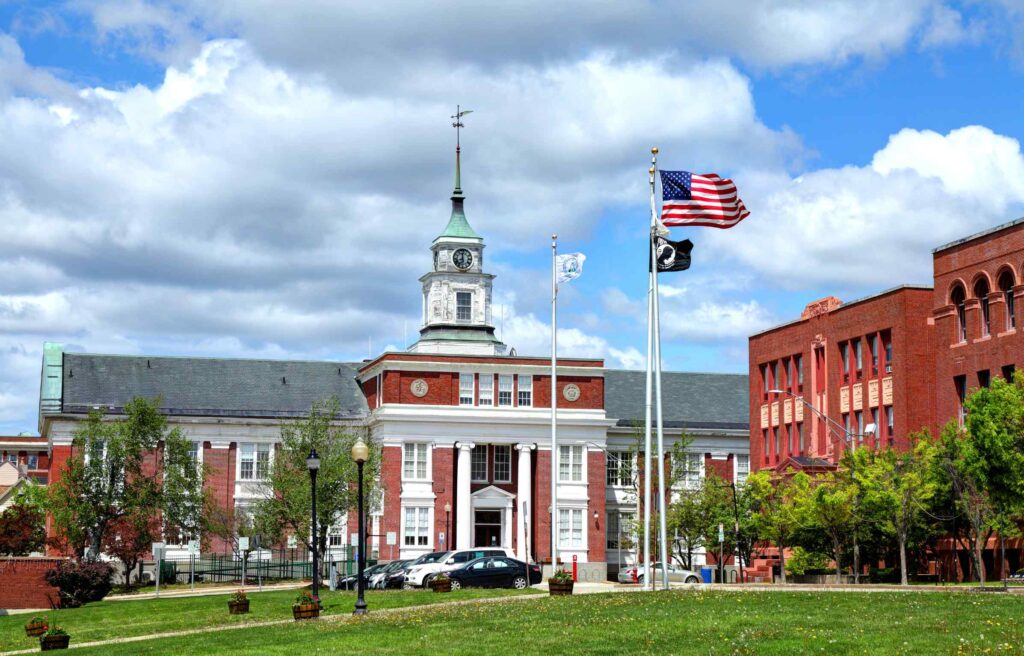 Historic red brick government building with clock tower and flags in Somerville, Massachusetts.