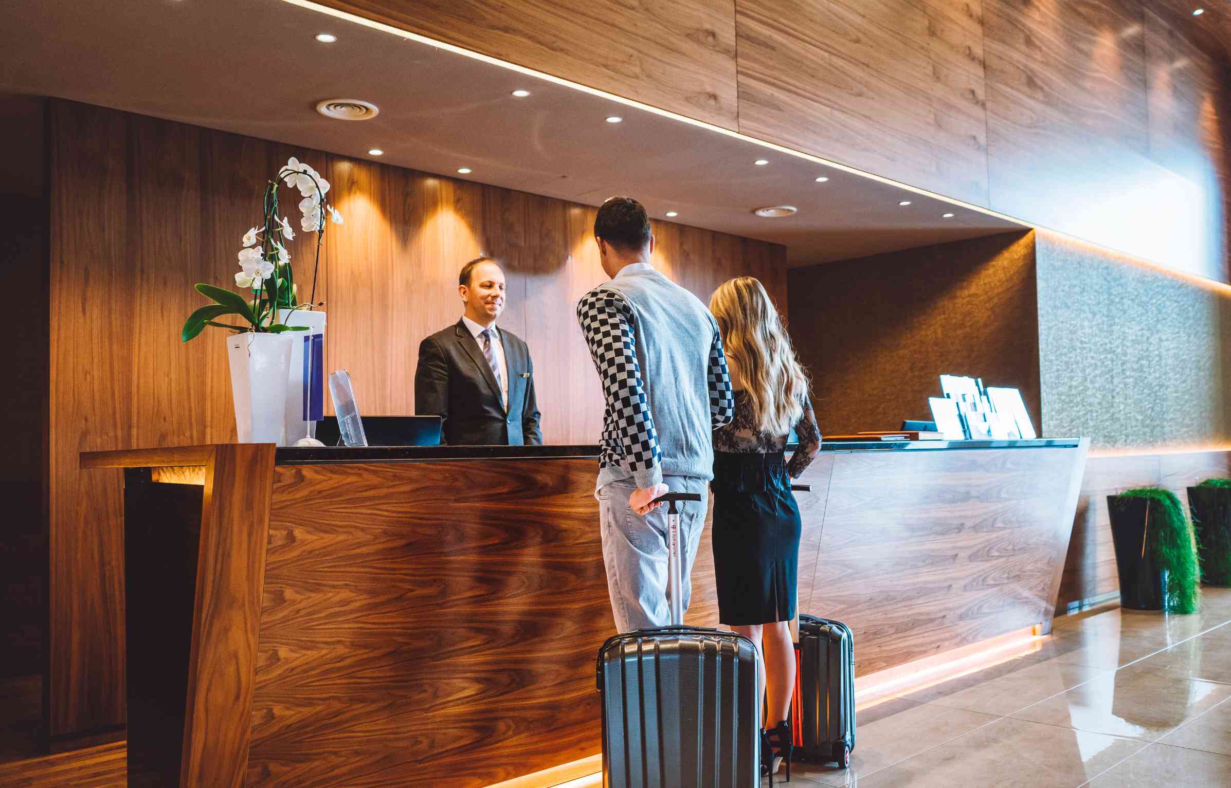 Couple in Radisson hotel checking in at the reception desk with luggage.