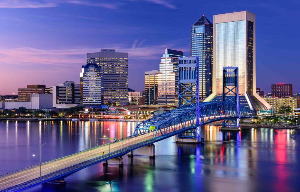 Jacksonville, Florida, skyline at night with illuminated bridge and reflections on the St. Johns River.