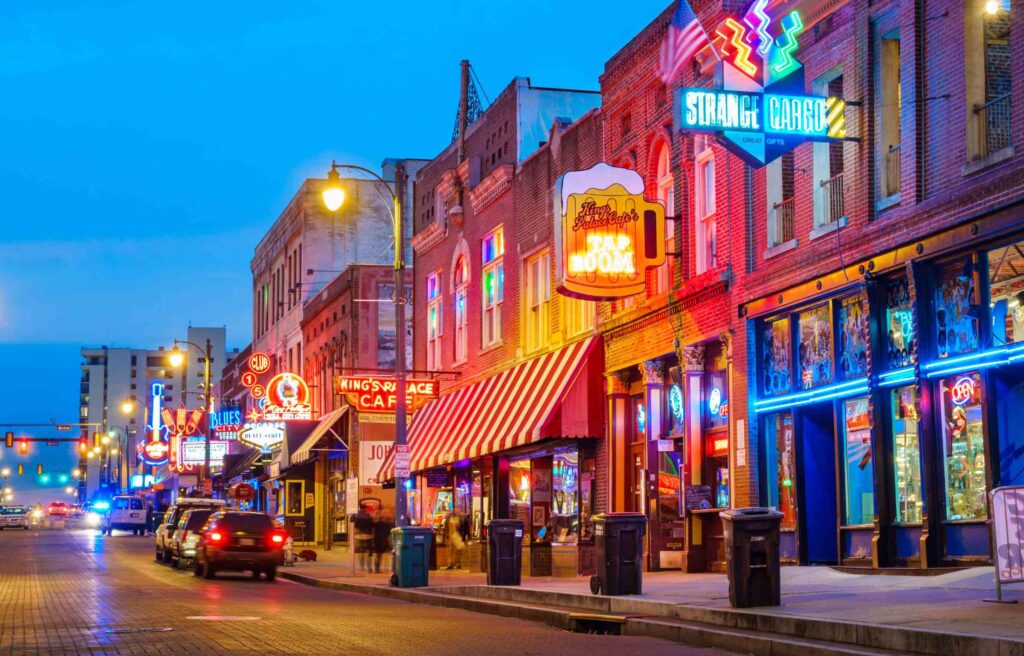 Beale Street in Memphis, Tennessee, is at night with colorful neon signs, bars, and live music venues.
