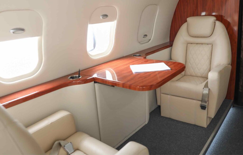 Luxury cabin with leather seating and a wooden table, illustrating how to use capital one miles for travel in premium comfort.