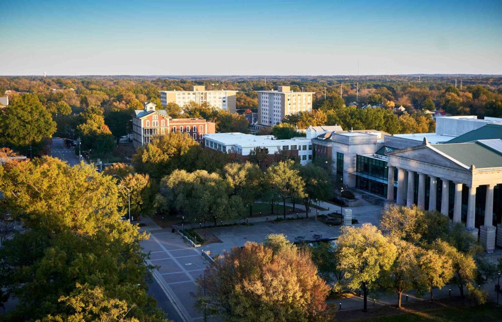 Aerial view of downtown Raleigh, North Carolina, with historic buildings, tree-lined streets, and a clear sky.