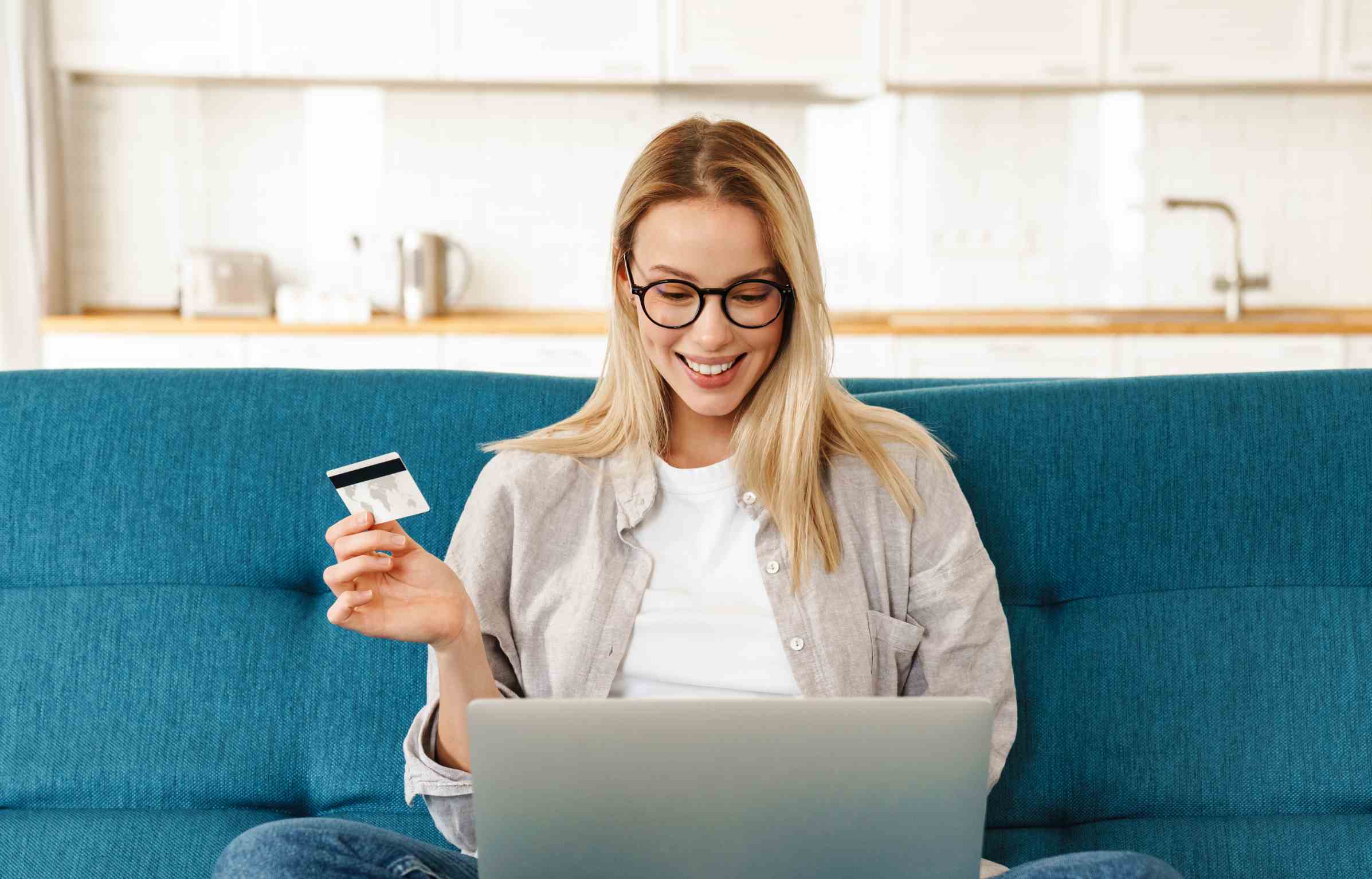 Smiling young woman checking Amex credit card fee on laptop.