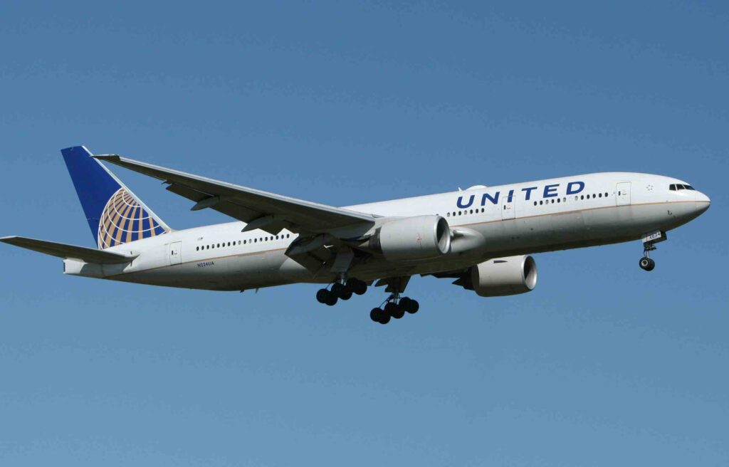 United Airlines aircraft flying in clear blue sky with landing gear extended, featuring united airlines starlink wi-fi.