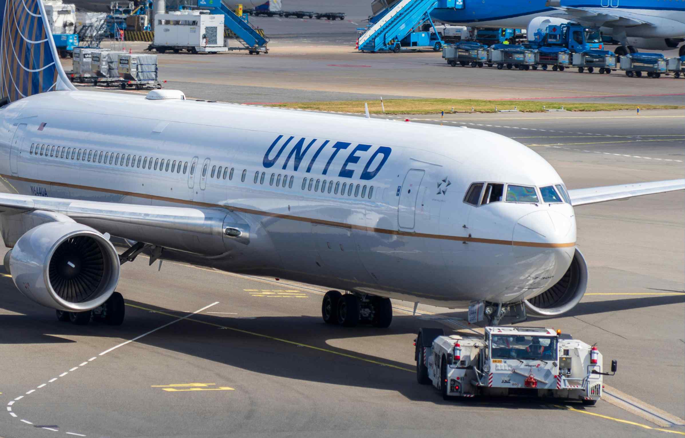 United Airlines Boeing aircraft on the tarmac being pushed back by a tow vehicle at the airport.