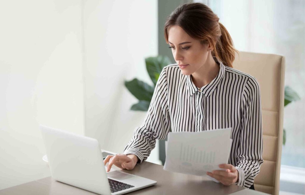 A woman reviewing tax documents on her laptop, researching the question “is relocation reimbursement taxable income.”