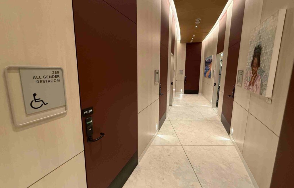 Modern hallway with accessible all-gender restrooms and artwork on the walls.