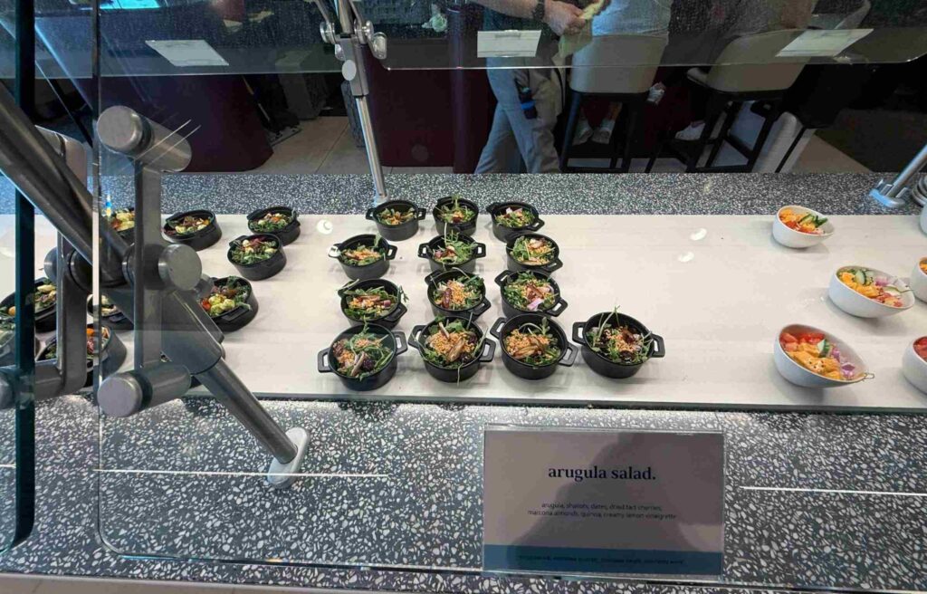 Small bowls of arugula salad with quinoa, almonds, and lemon vinaigrette on display in the Capital One Lounge.