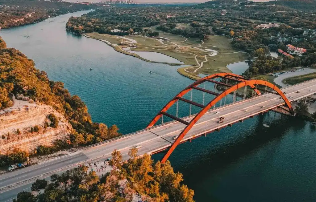 Austin, Texas, aerial view of the Pennybacker Bridge over the Colorado River surrounded by trees and hills.
