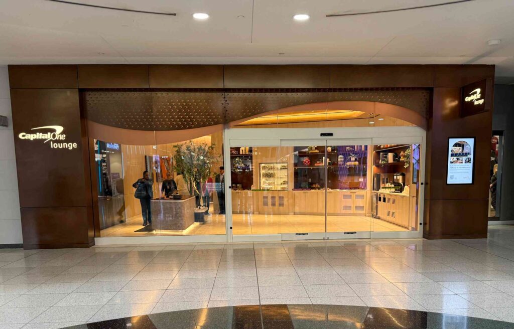 Entrance of capital one lounge at las vegas airport with travelers checking in at the modern reception.