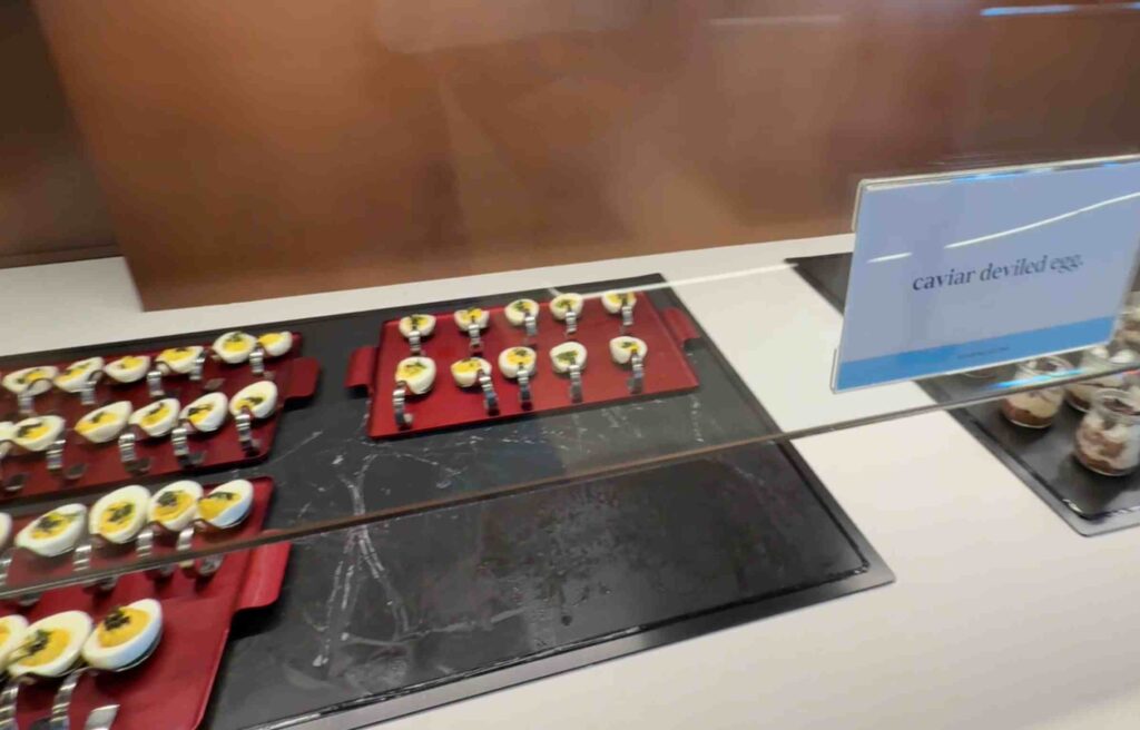 Bite-sized deviled eggs topped with caviar displayed neatly on red trays.