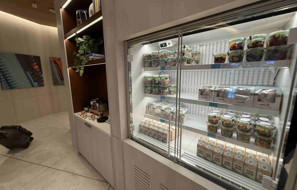 Refrigerated display filled with salads, boxed meals, and bottled drinks inside the lounge.