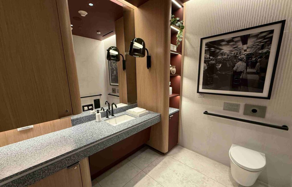 Restroom interior featuring a sleek sink area, artwork, and soft lighting.