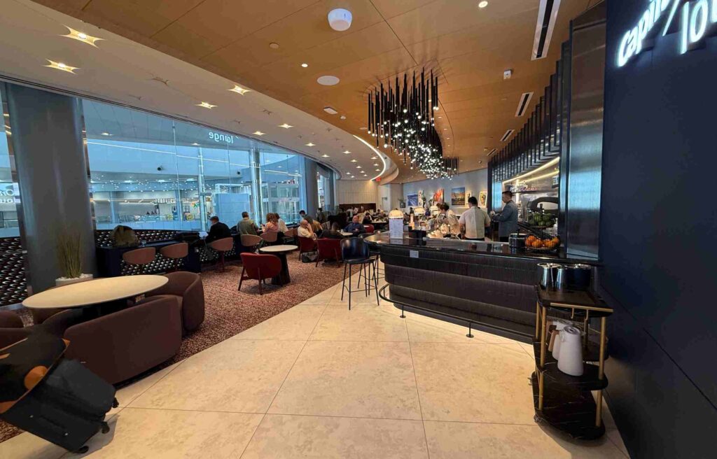 Guests seated in a spacious dining area with modern lighting and large windows overlooking the terminal.