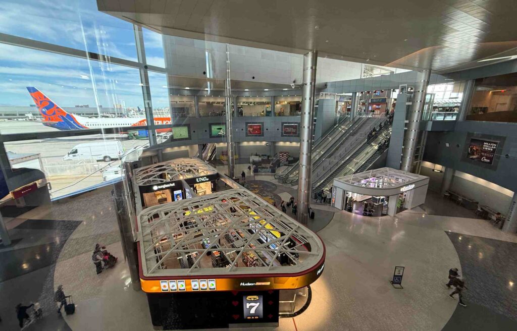Overhead view of Las Vegas Airport terminal with shops, escalators, and a parked aircraft outside.