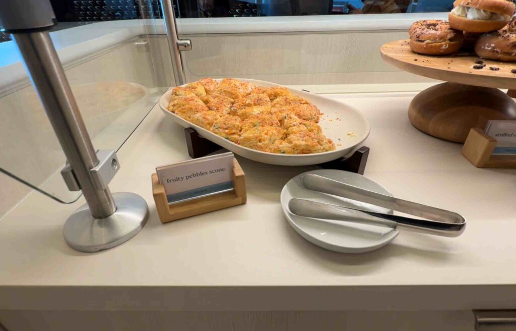 Tray of colorful scones sprinkled with Fruity Pebbles beside serving tongs.