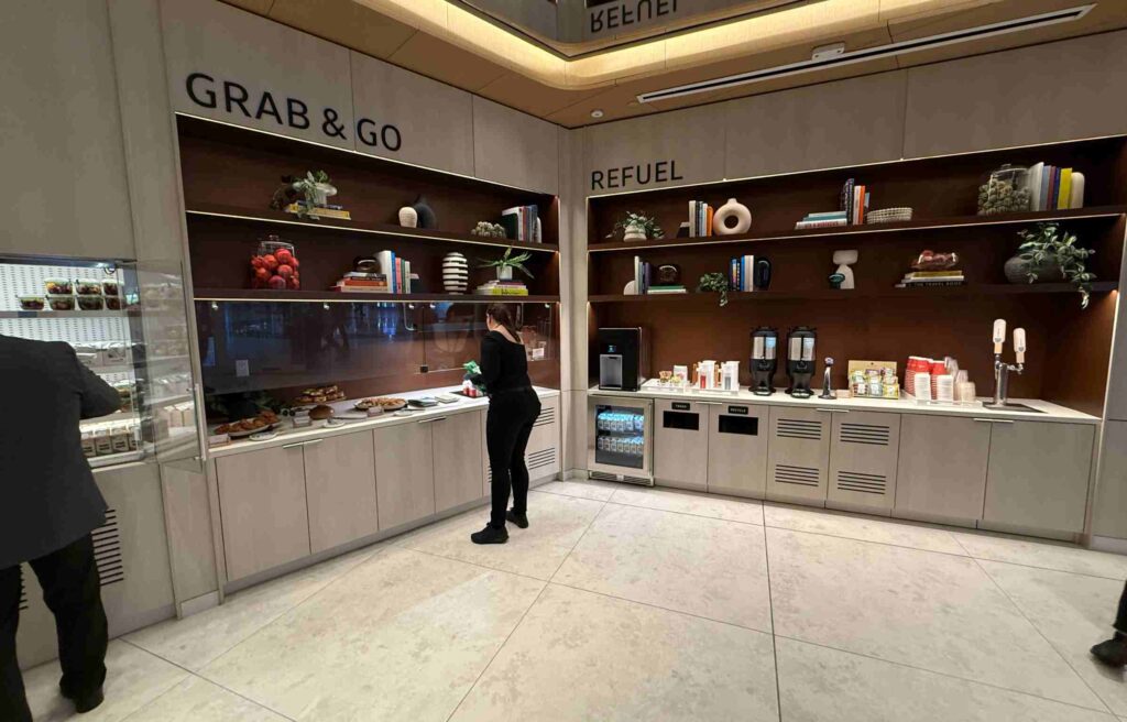 Lounge guest selecting food and drinks from Grab & Go and Refuel counters with modern shelving.