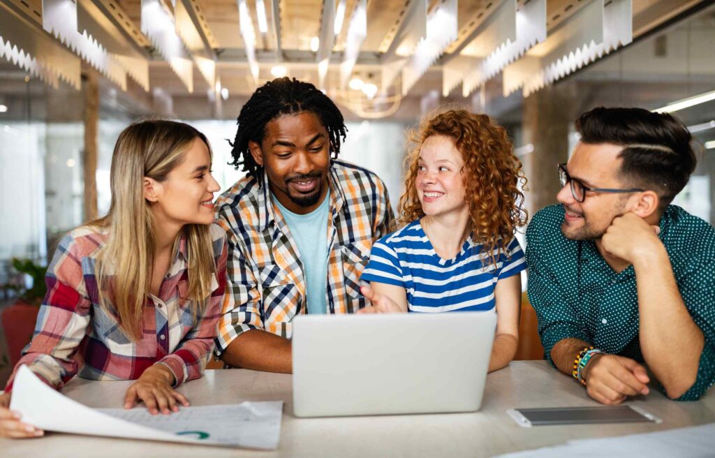 Happy employees collaborating in a modern office, reflecting the positive impact of an employee health benefit program.