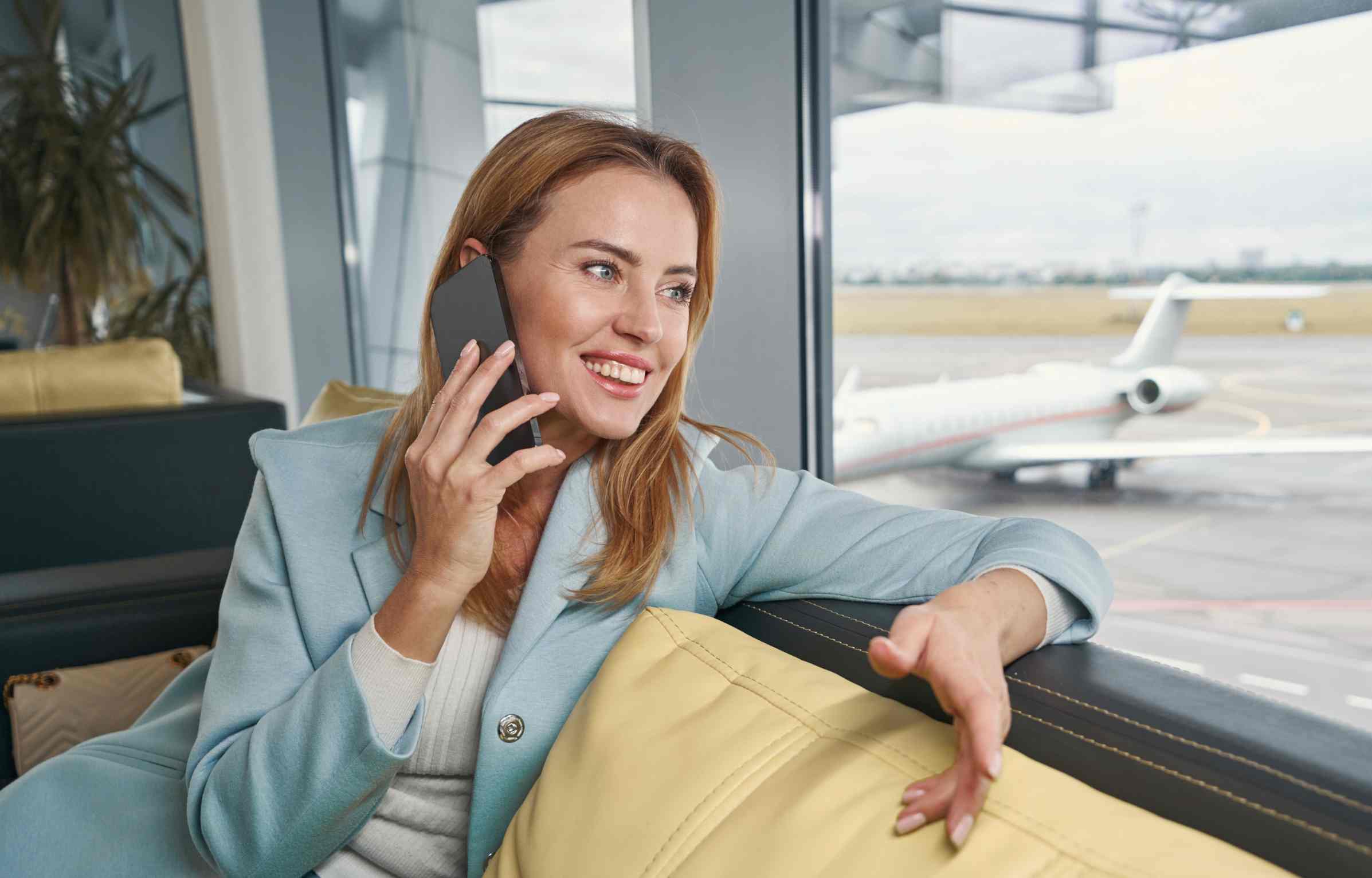 A woman is talking on the phone in the airport lounge.