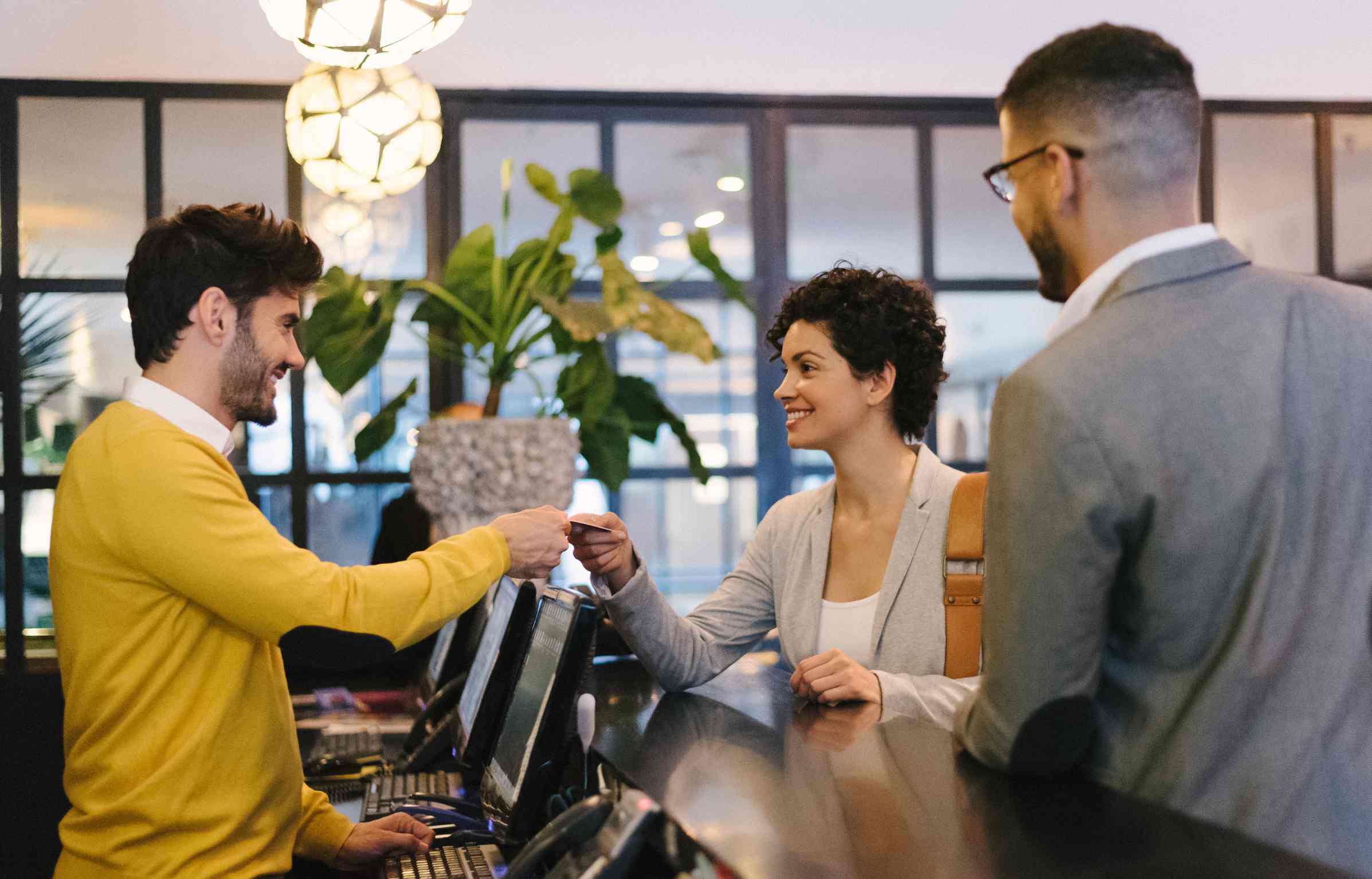 Business traveler handing a credit card to a hotel receptionist during Hilton Honors checkout.