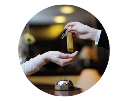 Hotel staff handing room key to guest at check-in counter.