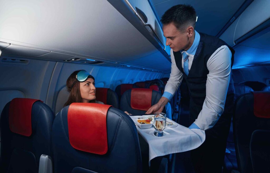 Male flight attendant serving a meal to a woman on a Southwest flight, showing comfort and perks tied to how to earn the southwest companion pass.