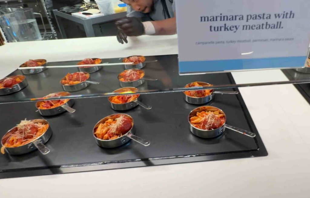 Small servings of pasta with turkey meatballs and cheese plated on a buffet tray.