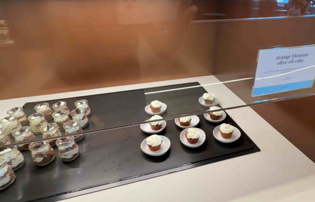 Mini cakes topped with whipped cream and citrus flavor displayed under warm light.