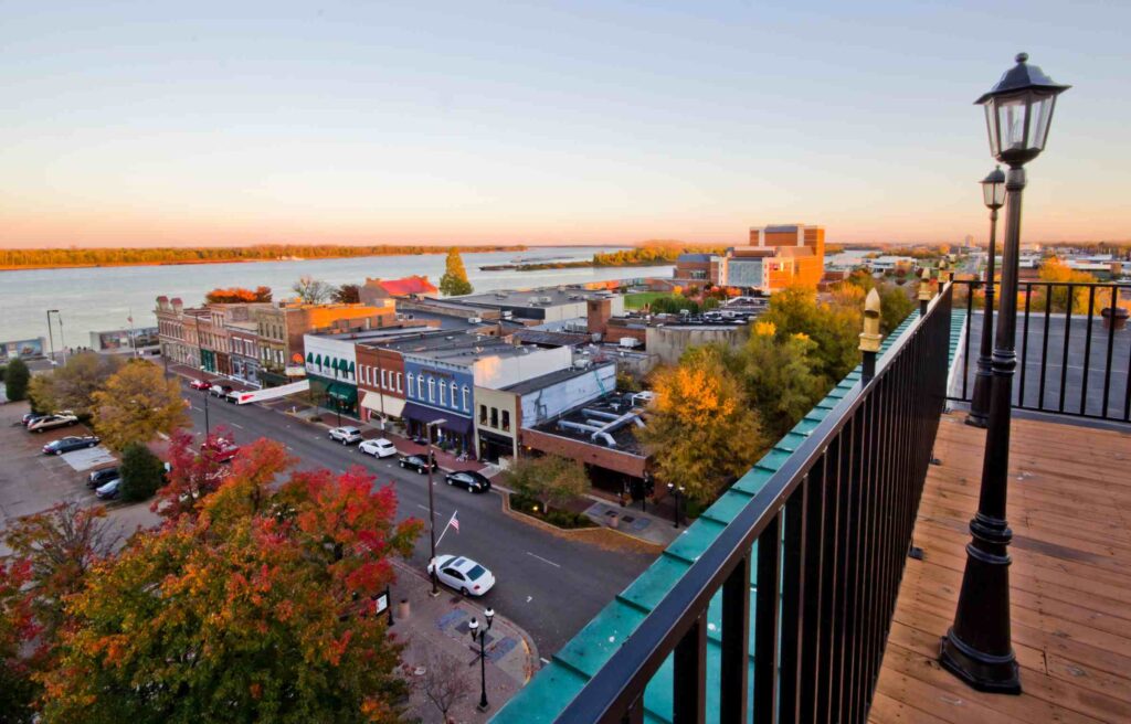 Aerial view of downtown Paducah, Kentucky, at sunset with historic buildings, colorful autumn trees, and the Ohio River in the background.