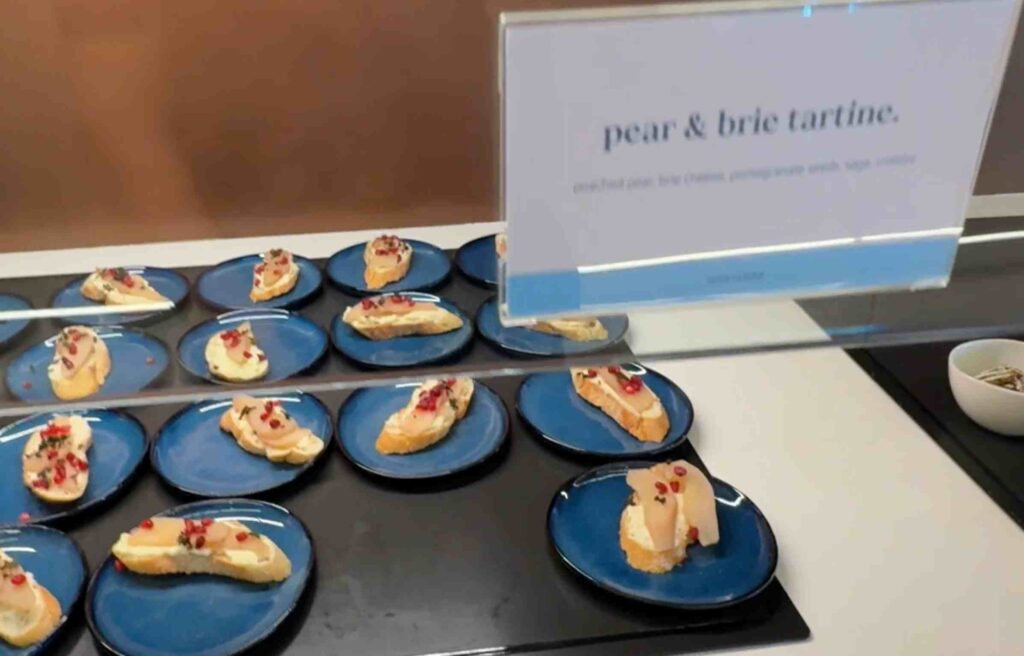 Toasted bread topped with brie cheese, pear slices, and pomegranate seeds on blue plates.
