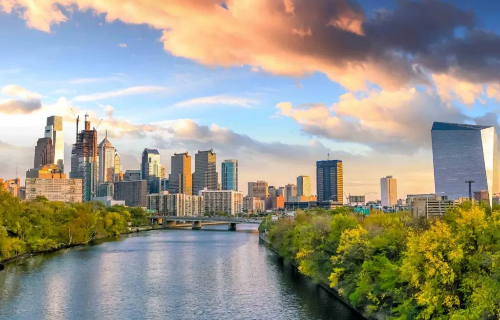 Philadelphia, Pennsylvania, skyline with modern skyscrapers and the Schuylkill River at sunset.
