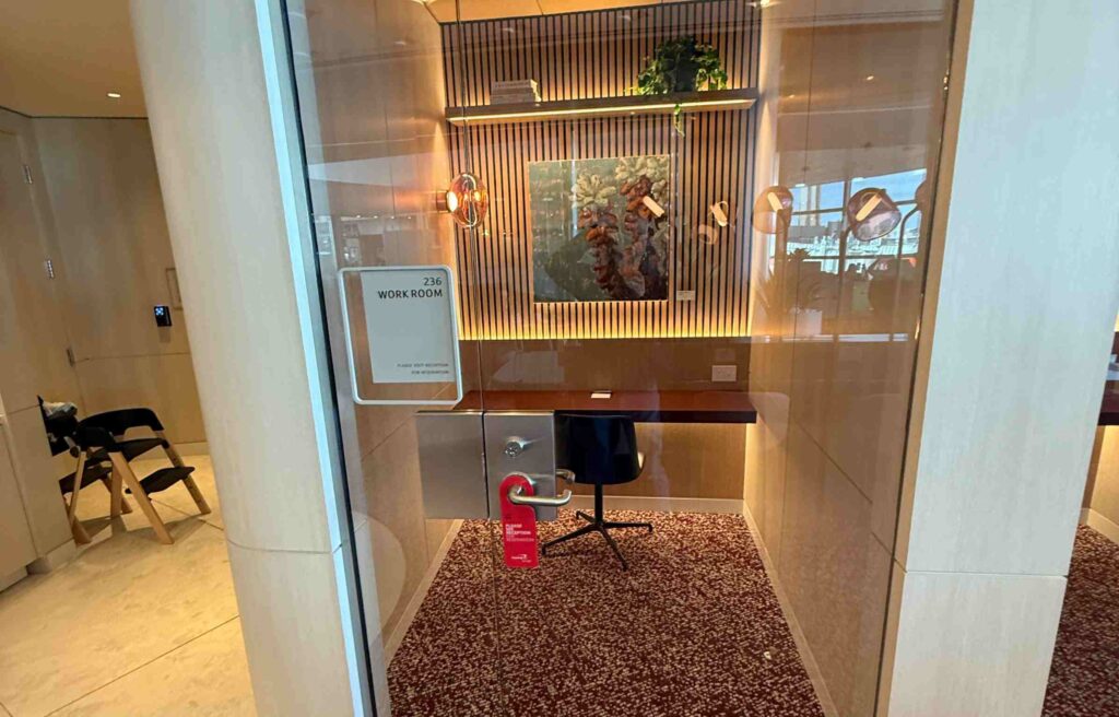 Compact work room with a desk, chair, and warm lighting offering privacy inside the lounge.