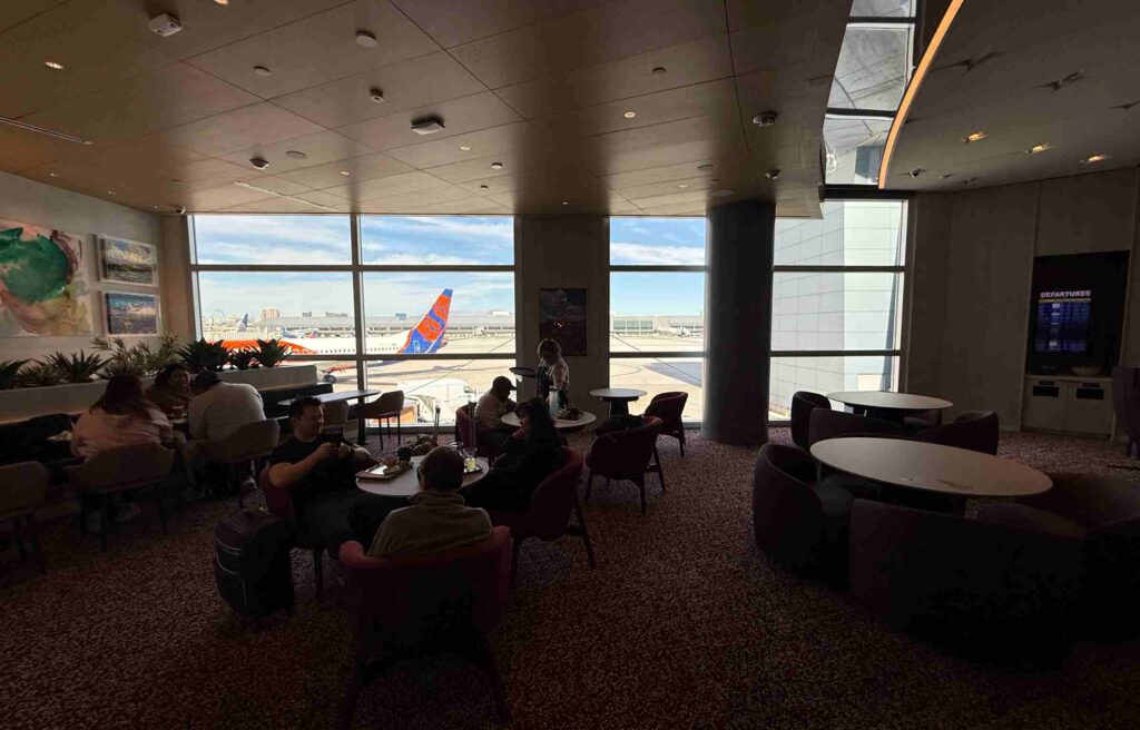 Guests seated near large windows overlooking planes at Las Vegas Airport.