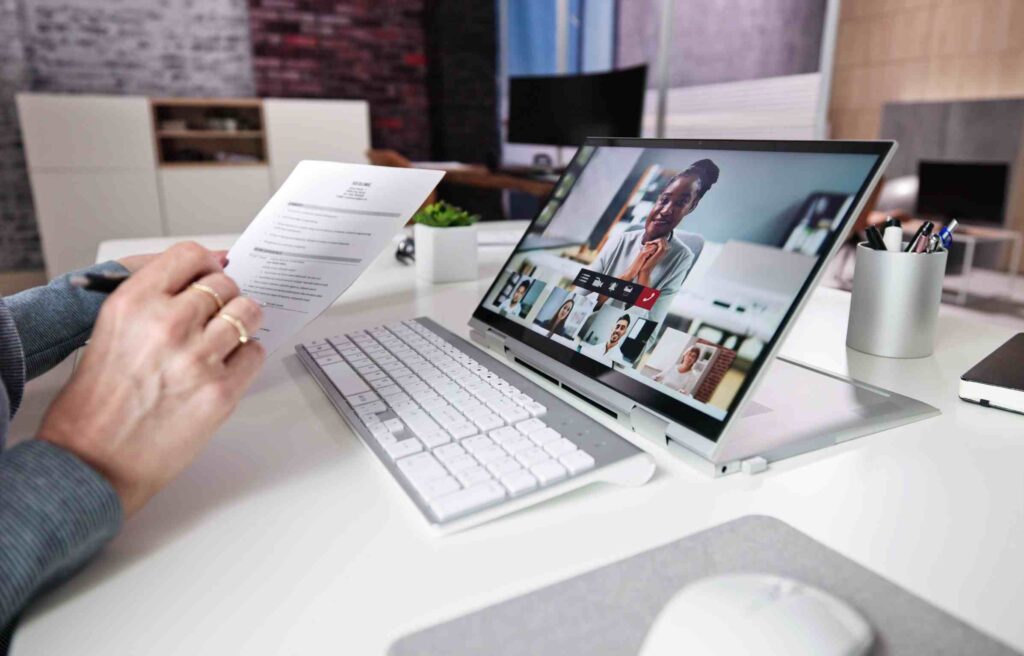 Employer reviewing a resume during an online video interview on a laptop, showing a discussion related to relocation vs remote hire cost analysis.