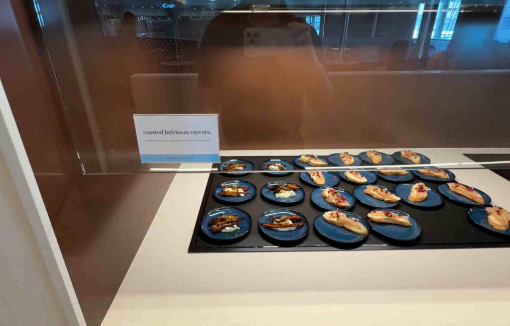 Blue plates showcasing roasted heirloom carrots topped with herbs and sauce.