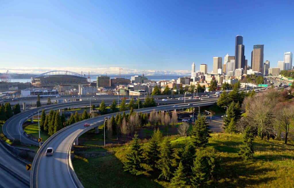 Seattle, Washington, city skyline with highway view, stadium, and waterfront in the distance.