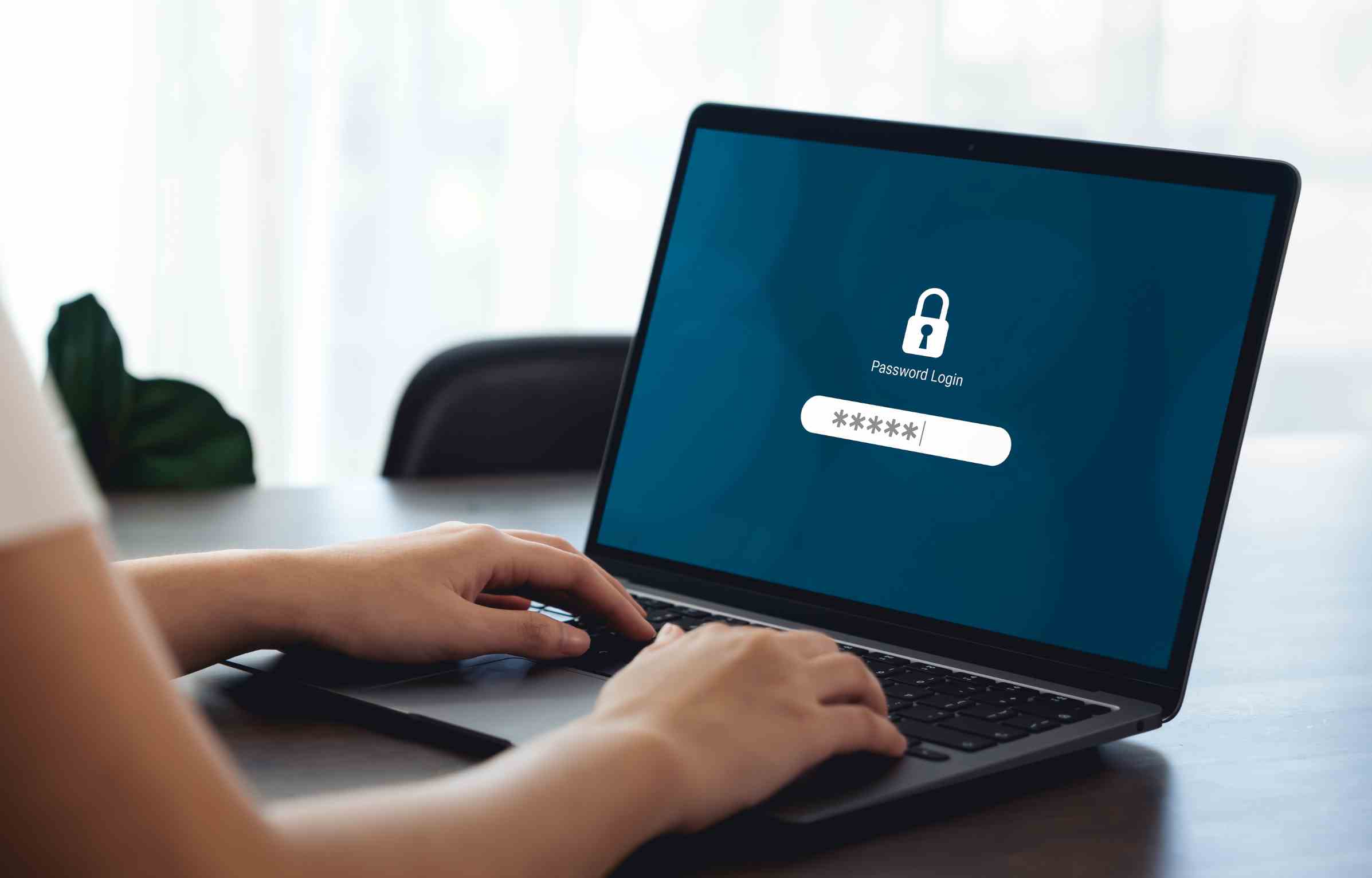 A person typing on a laptop showing a password login screen with a lock icon, representing secure digital access and password protection.