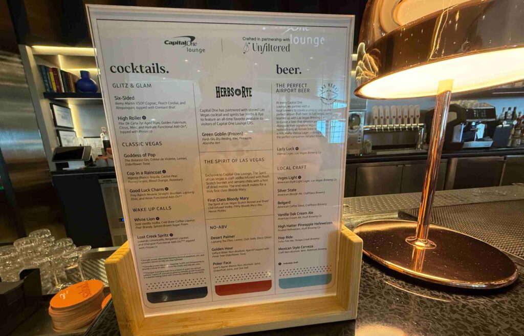 Capital One Lounge drink menu displayed on the bar counter under a warm lamp.