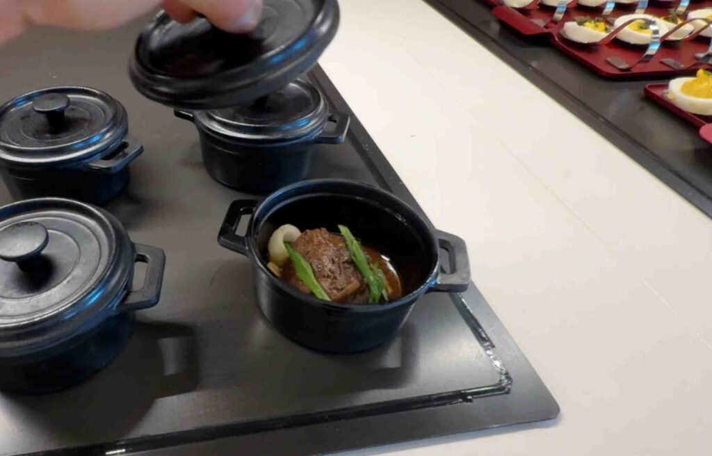 Small black pots filled with tender short rib and vegetables in rich sauce.