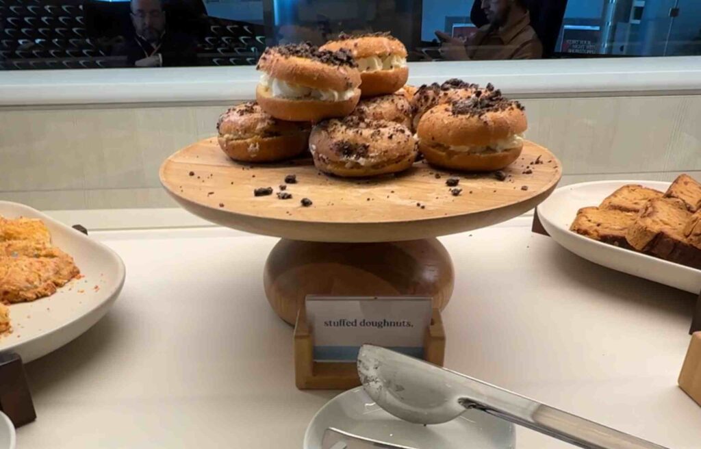 Wooden stand displaying stuffed doughnuts topped with crushed chocolate crumbs.