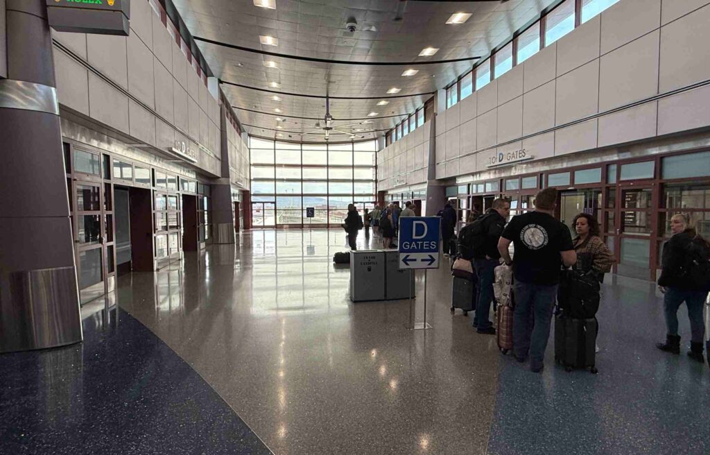Passengers with luggage waiting in line at Las Vegas Airport near D Gates concourse.