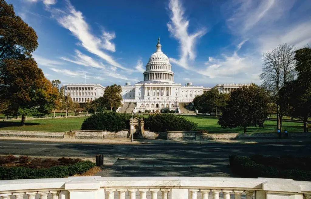 Washington, DC, United States Capitol building with green lawns and blue sky.

