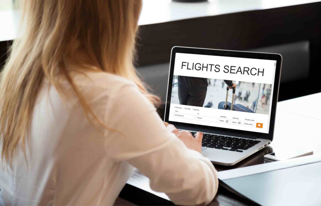 A woman is booking a flight early on her laptop while learning how to redeem alaska airlines companion fare for better travel savings.