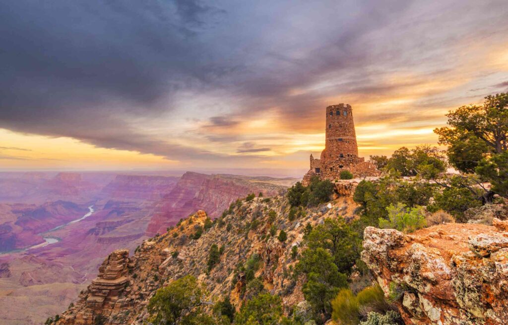Desert View Watchtower rises above the Grand Canyon’s South Rim at sunset, a scene that often inspires people relocating to arizona to appreciate the landscape’s dramatic depth and color.