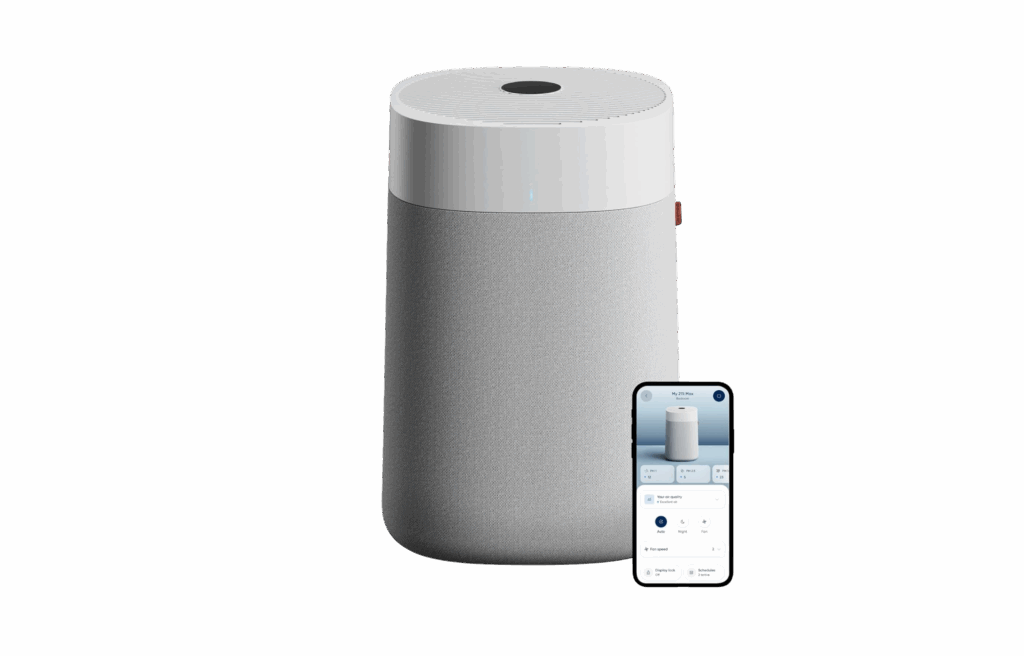Blueair air purifier in grey with a smartphone displaying its control app.