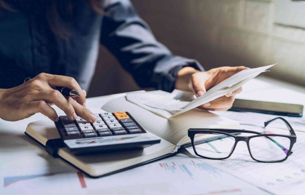 A person using a calculator and reviewing documents at a desk.