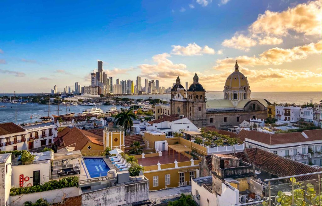 Aerial view of Cartagena, Colombia with historic buildings, colorful rooftops, and a modern skyline overlooking the sea.