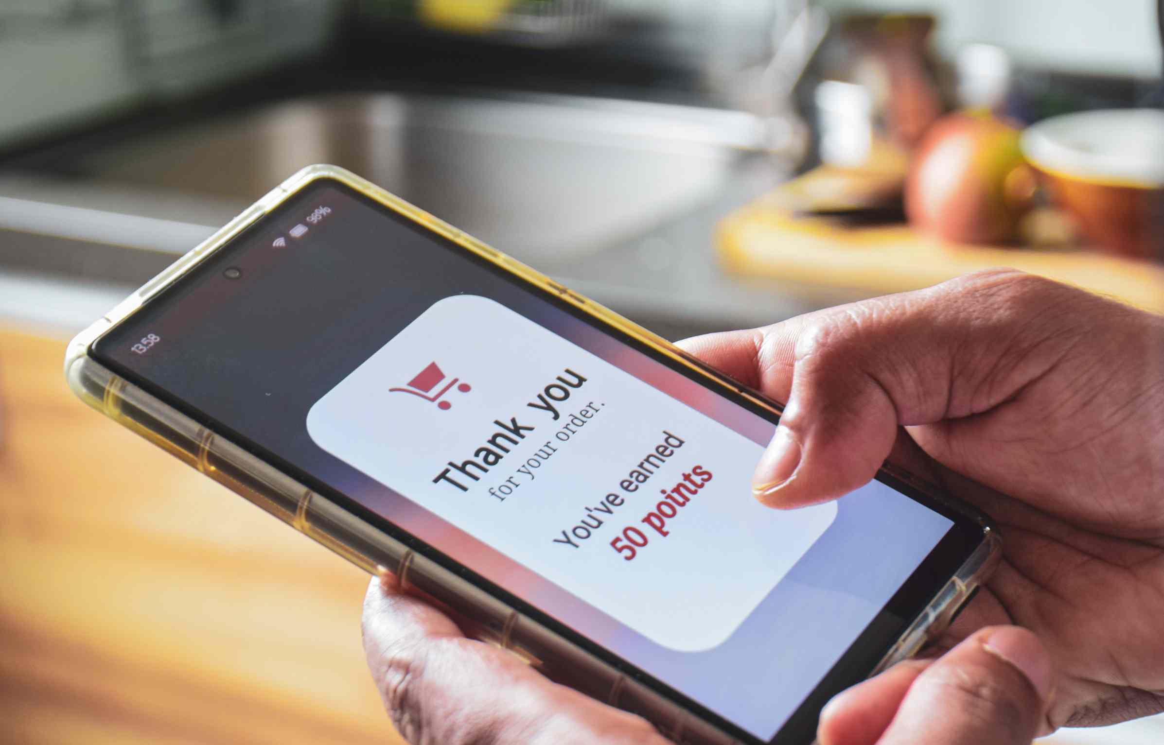 A person holding a phone showing “You’ve earned 50 points,” illustrating digital purchase and reward points confirmation.